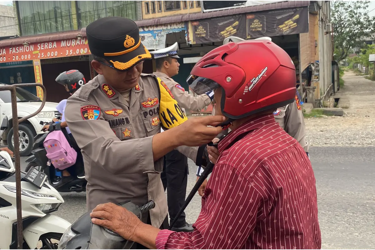 Kapolres Aceh Utara AKBP Nanang Indra Bakti membagikan helm Standar Nasional Indonesia (SNI) gratis kepada pengendara roda dua dan penumpang anak yang tidak memakai helm di kawasan Pos Lantas Kota Lhoksukon, Rabu, 24 Juli 2024. Foto: Humas Polres Aceh Utara