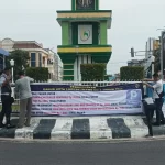 Petugas Dishub Lhokseumawe memasang spanduk tarif parkir di bundaran Tugu Banda Aceh. Foto: Istimewa