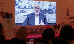 Ismail Haniyeh, berbicara dalam pesan rekaman yang ditayangkan di layar selama acara pers untuk Lembaga Internasional Al Quds di Beirut, Lebanon, pada 28 Februari 2024. Foto: Mohamed Azakir/Reuters
