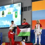 Lifter Aceh Zul Ilmi mengibarkan bendera Palestina usai memastikan kemenangan di kelas 96 kilogram putra. Foto: MC PON Aceh