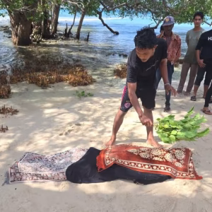 Warga menutupi jenazah pria yang ditemukan di lokasi wisata Pantai Pasir Putih Krueng Raya