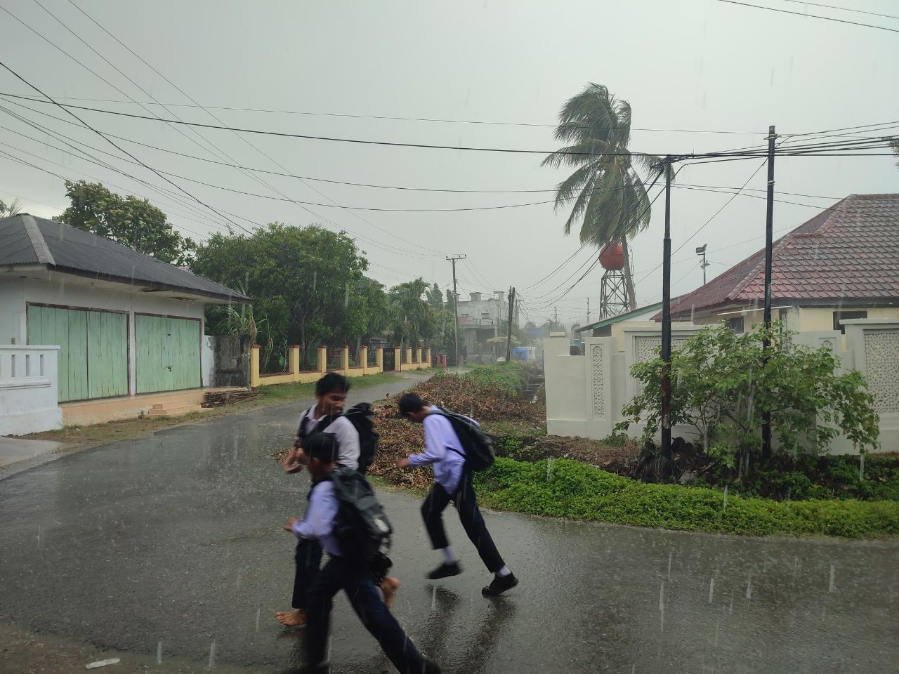 Anak sekolah berlarian saat hujan di Gampong Jawa Idi Rayeuk
