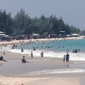 Wisatawan menikmati pemandangan pasir putih dan laut biru di Pantai Lampuuk Lhoknga, Aceh Besar saat libur Lebaran 2026.